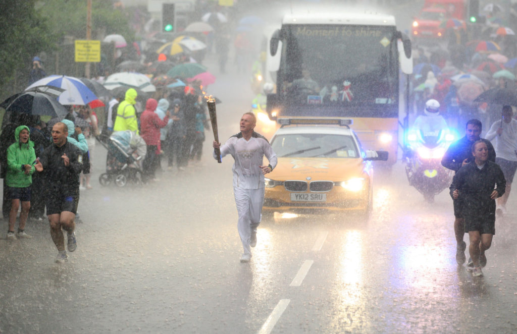 Glenn Chambers carries the Olympic Flame on the Torch Relay leg between Edwinstowe and Mansfield in severe rain June 28, 2012. Picture by Chris Radburn, PA